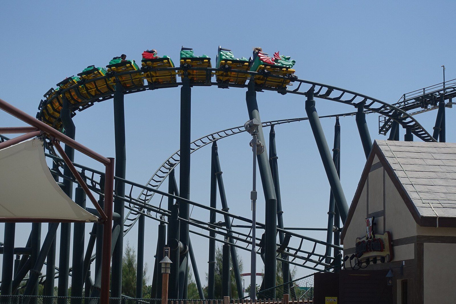 Dubai fun at a theme park: a green dragon roller coaster train races along a dark steel track