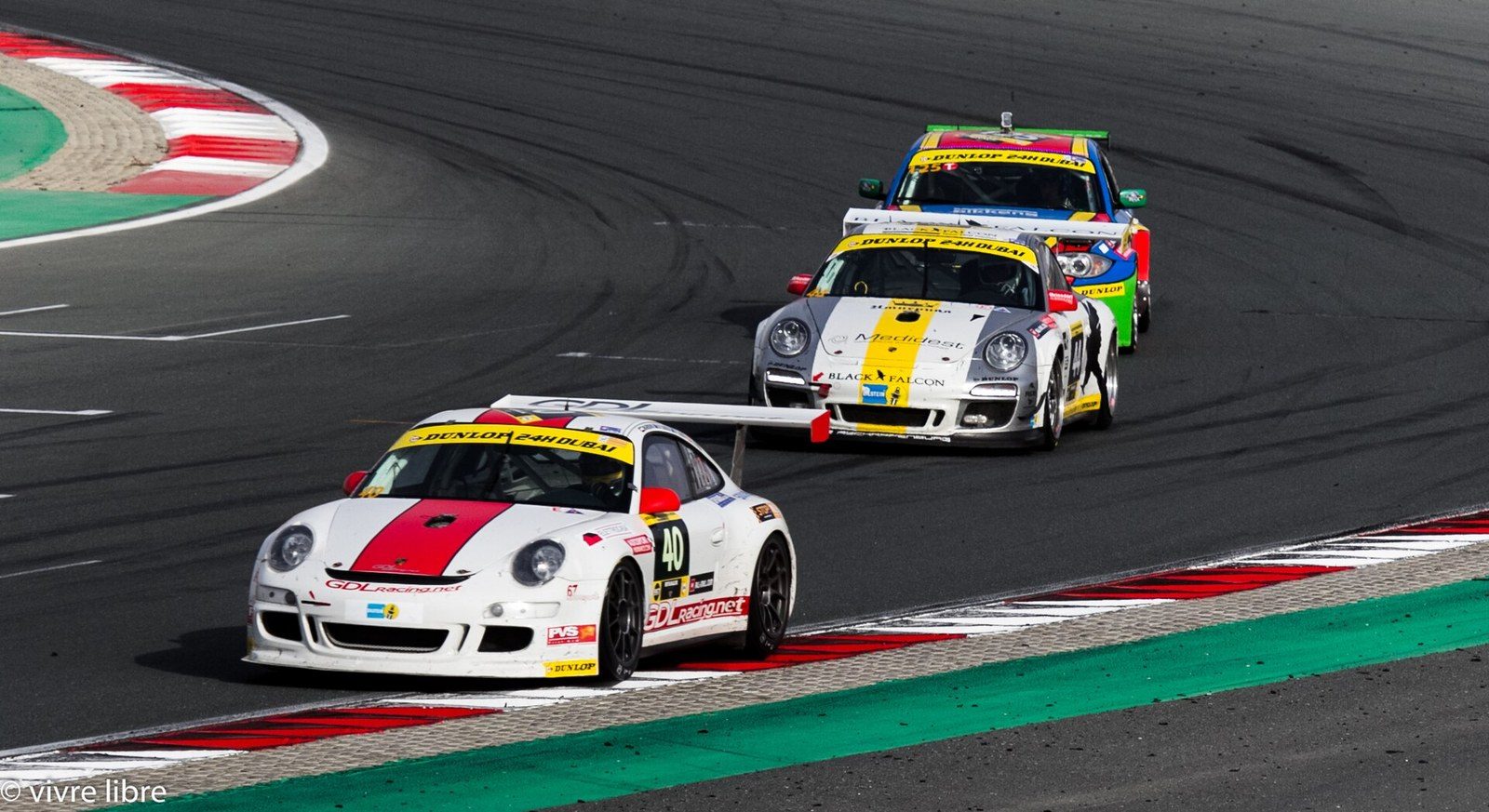Dubai racing: three GT race cars in white, silver and yellow liveries take a bend on the circuit