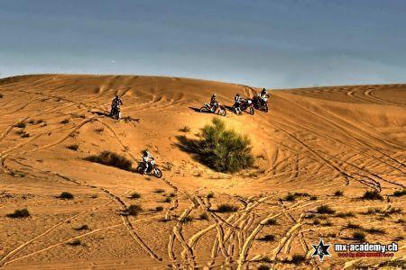 Dune buggy Dubai alternative: riders on motocross bikes spread out across a sandy dune slope with green shrubs