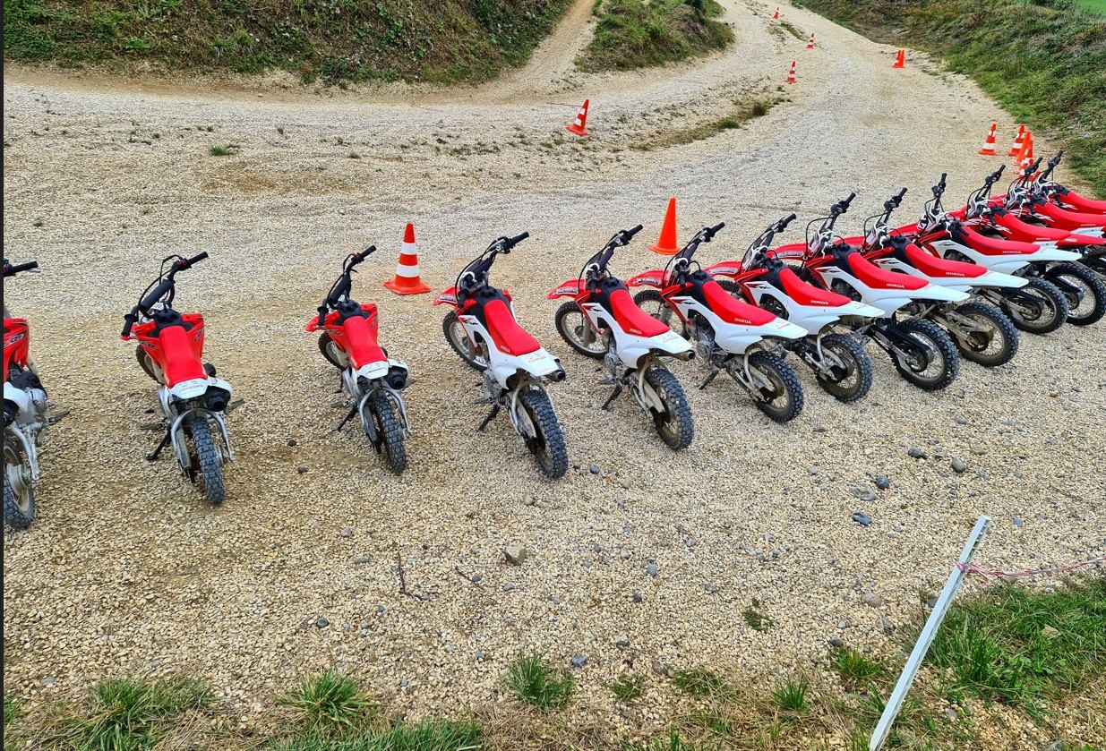 Motocross holiday in Switzerland: small red Honda rental bikes lined up on gravel beside orange cones