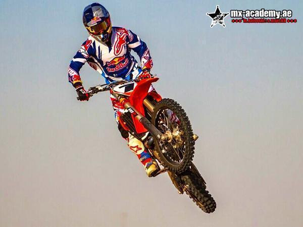 Motocross training in Dubai: rider in Red Bull gear and helmet jumps a red bike high against a pale sky