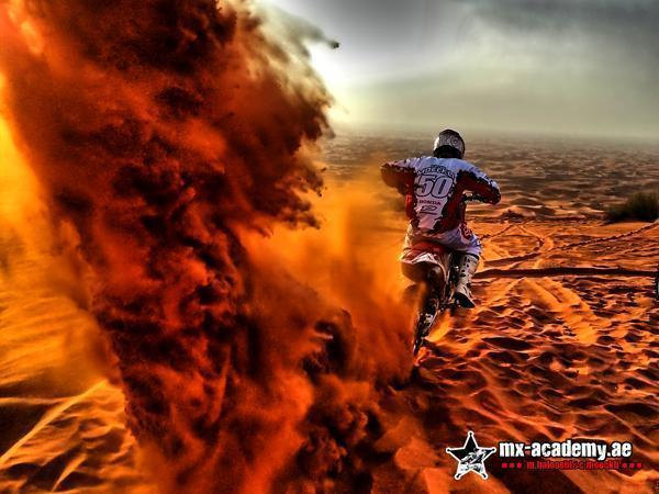 Off-road motorbike rental: rider number 50 heads into the desert while a huge cloud of red sand rises beside him