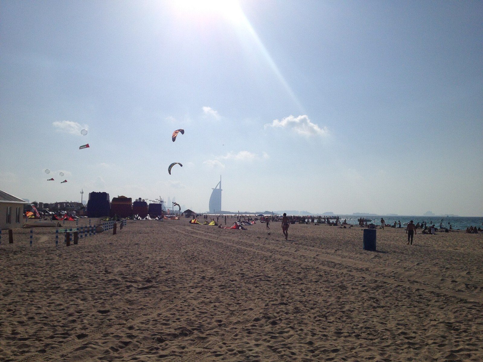 Outdoor activities in Dubai: kites fly over a wide sandy beach, with the sail-shaped Burj Al Arab far away