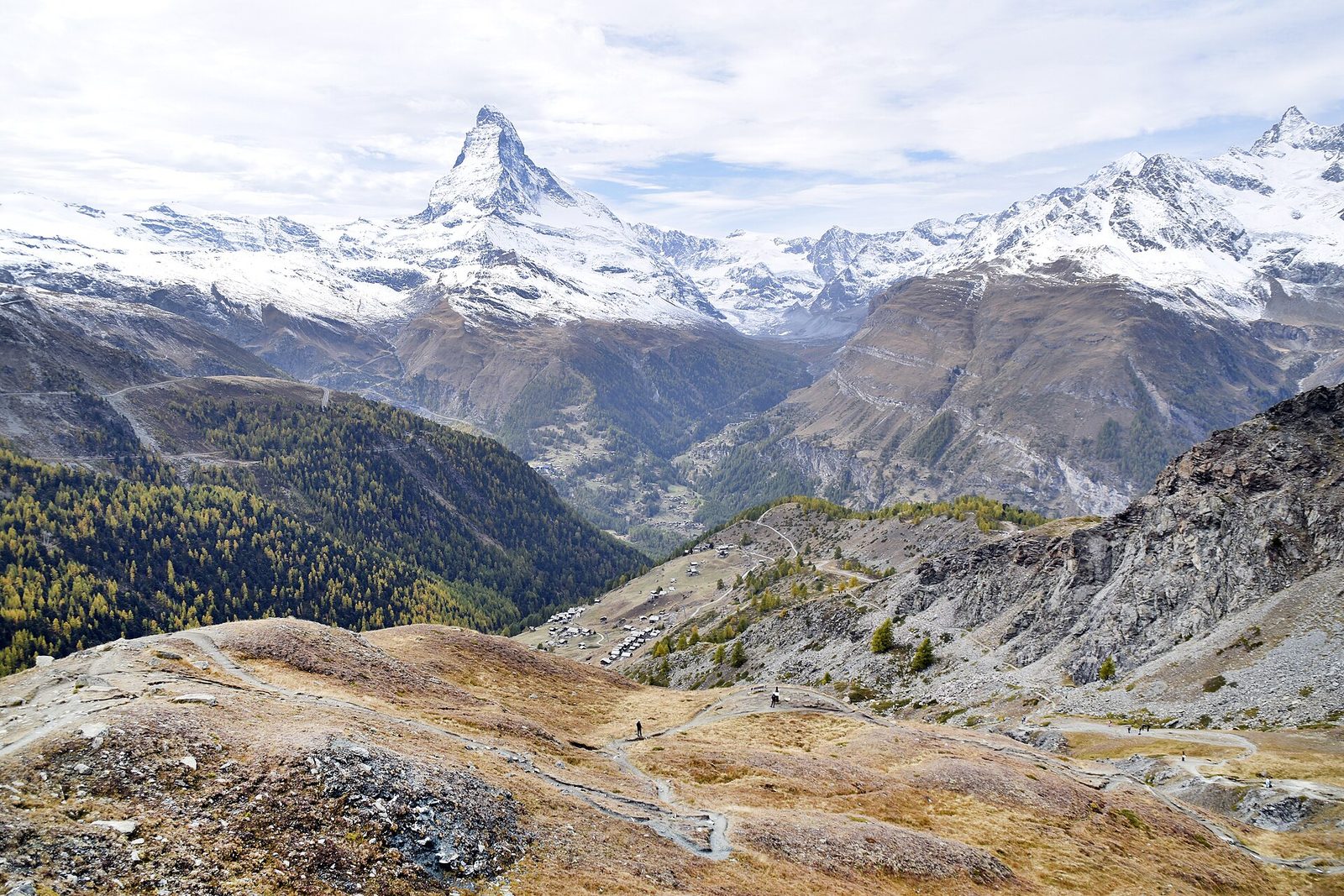 Popular sports in Switzerland: hikers on a mountain trail with the snow-capped Matterhorn in the distance
