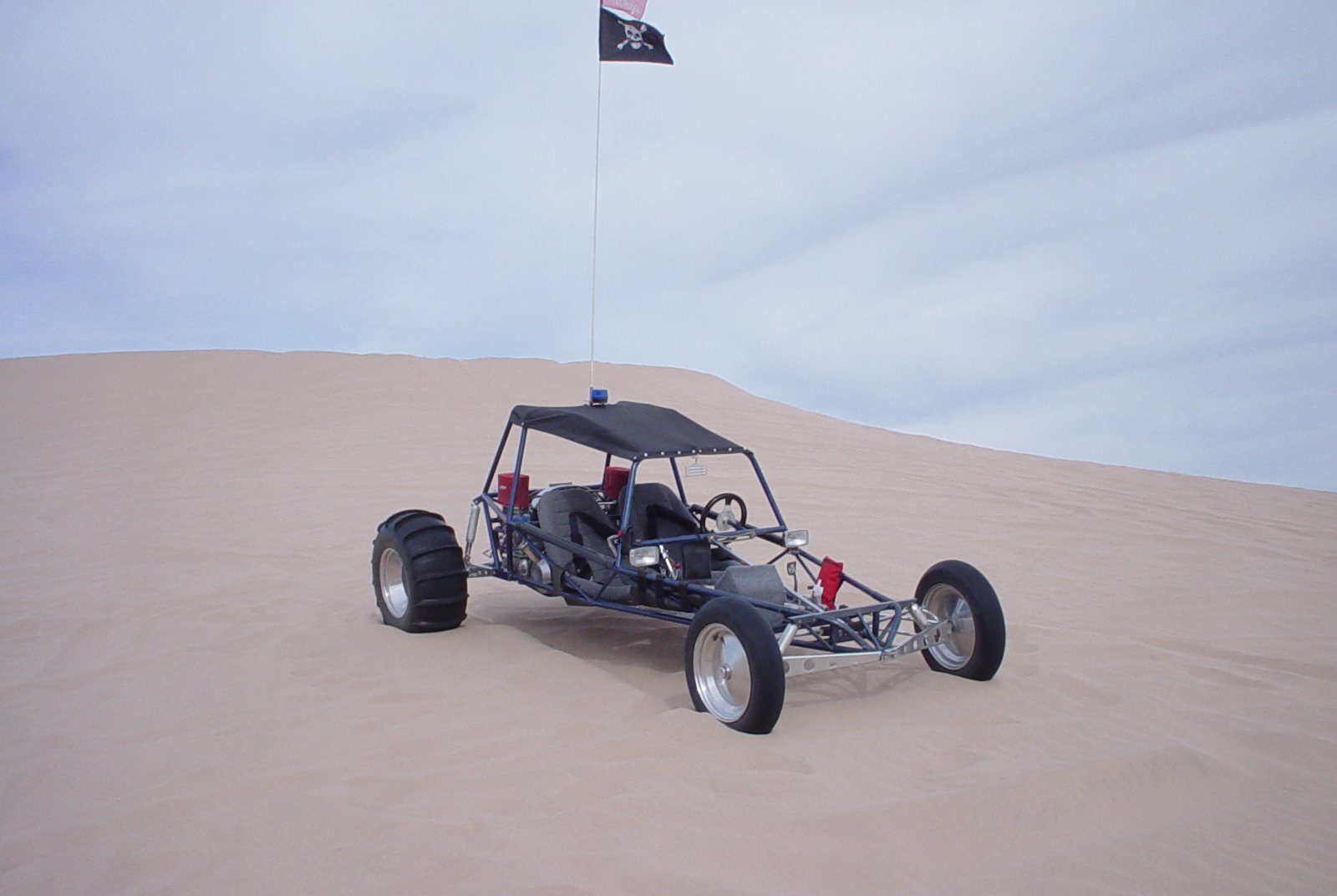Self-drive dune buggy: an open buggy with a tubular frame, bucket seats and wide rear tyres stands on a pale dune