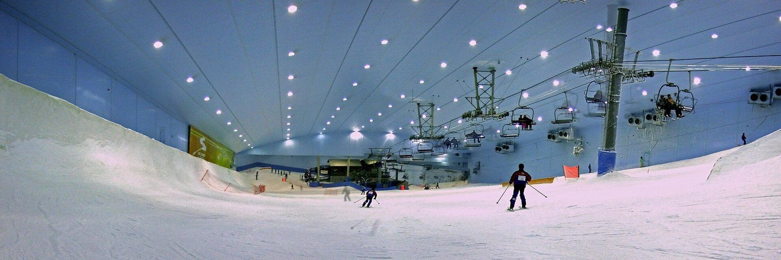 Sports activities in Dubai: skiers on an indoor snow slope under a lit ceiling, with a chairlift above them