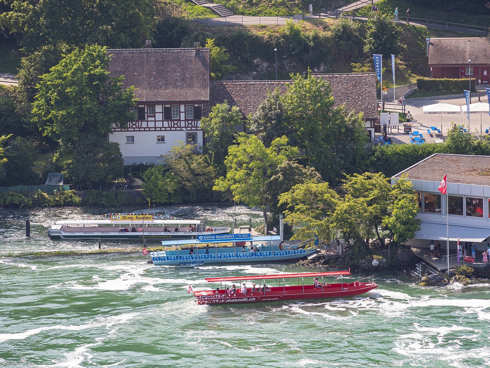 Switzerland activities on the water: red, blue and white tour boats at a landing stage below a half-timbered house