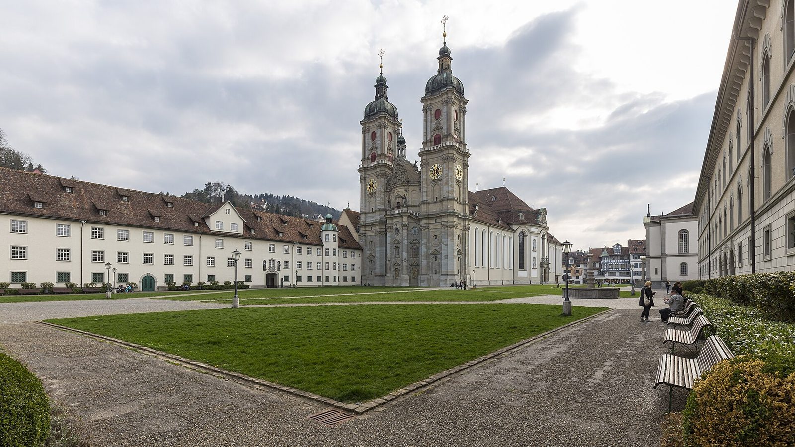 Switzerland sightseeing on a day trip: the twin-towered cathedral and abbey buildings of St. Gallen behind a lawn