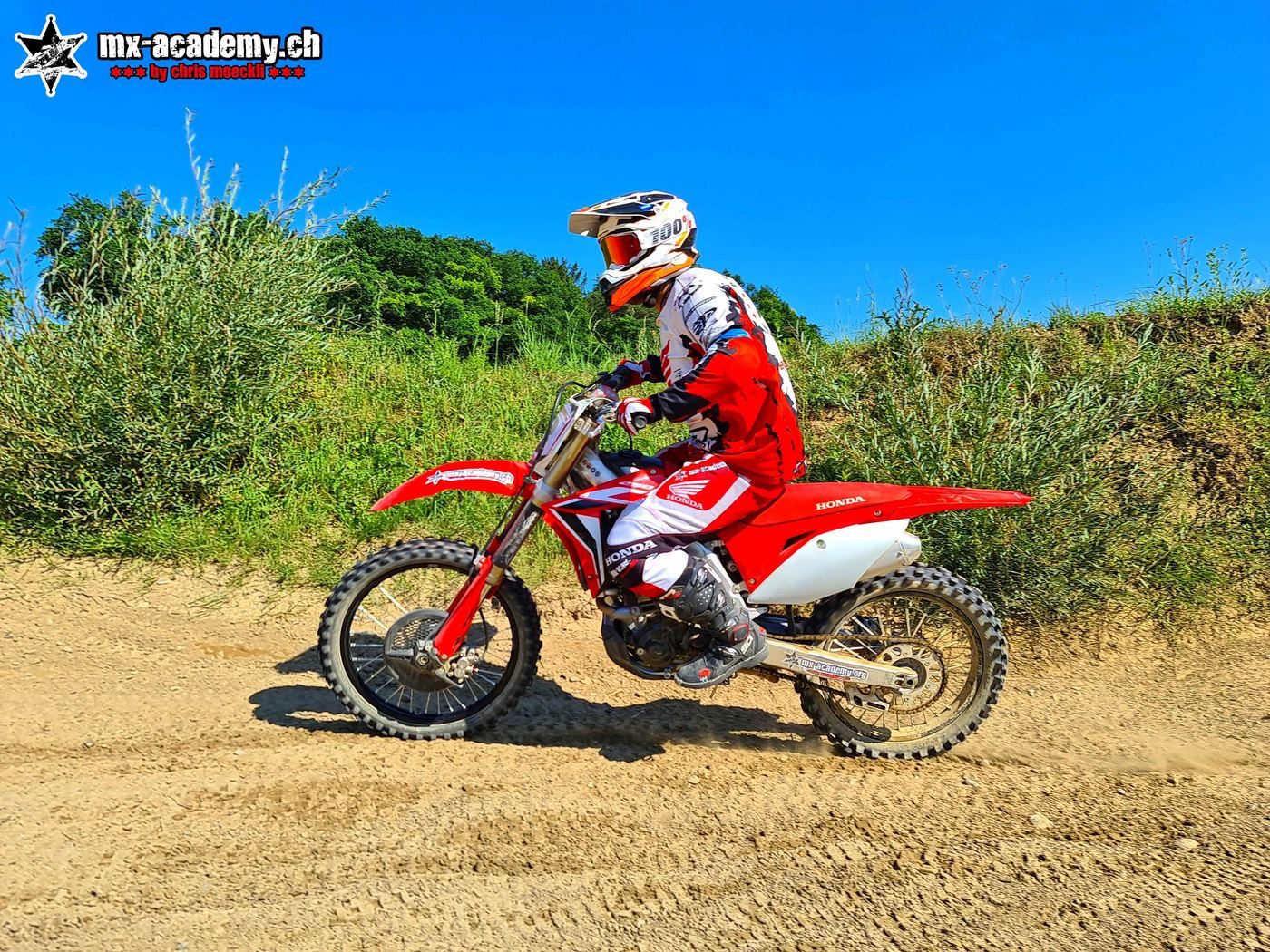 Switzerland sports to try in a day: a rider in red and white gear on a red Honda on a sandy track, blue sky