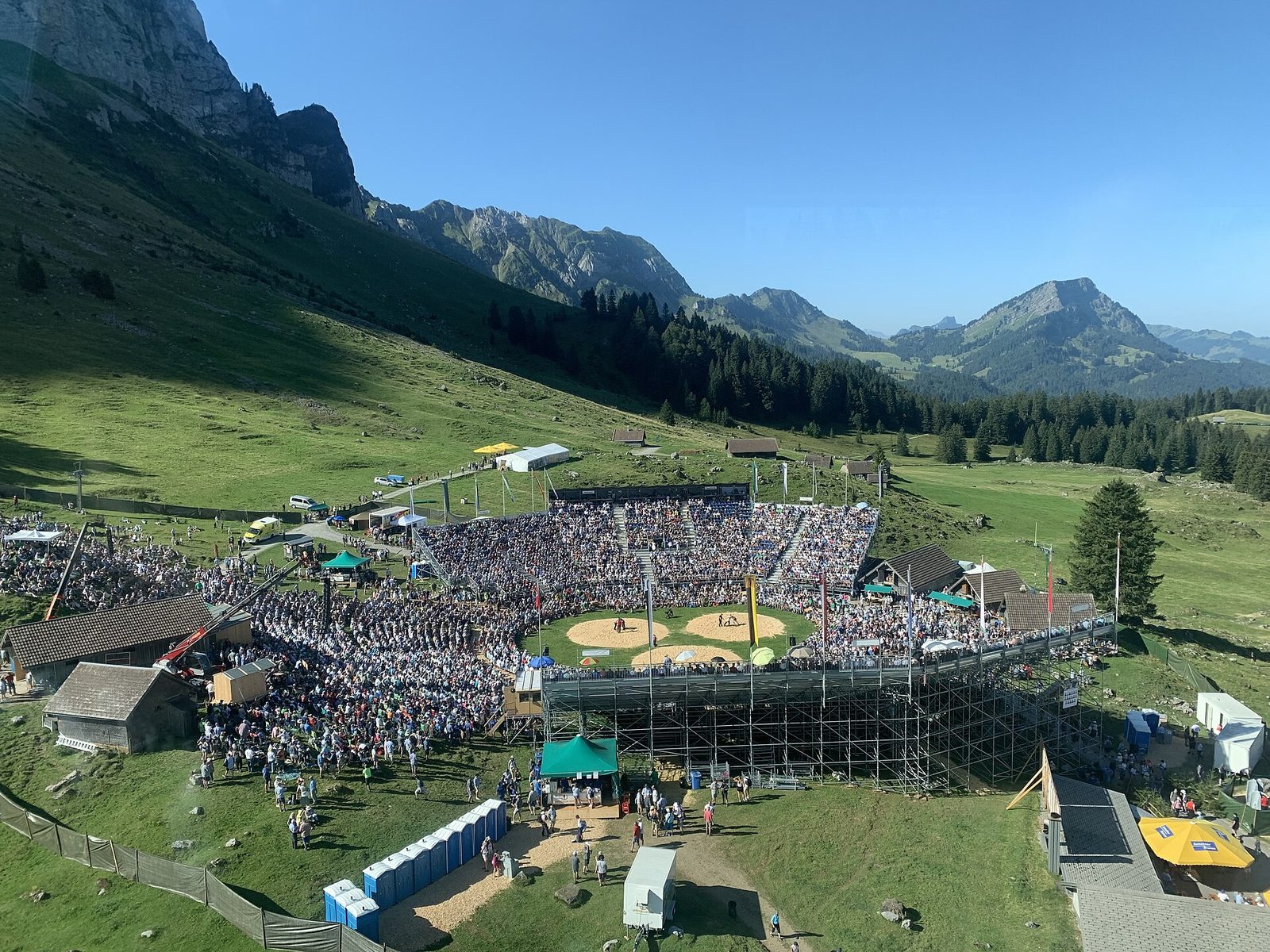 Switzerland sports tradition: crowds in a stand around sawdust rings at a Schwingen festival in the mountains