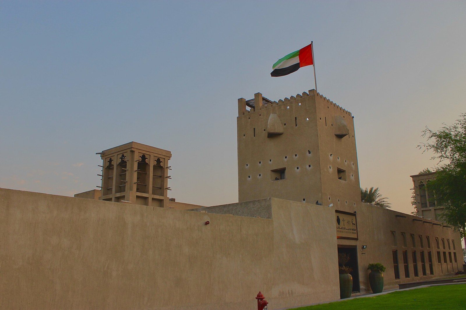 What to do in Dubai in one day: a sand-coloured fort-like building with a square tower and the UAE flag
