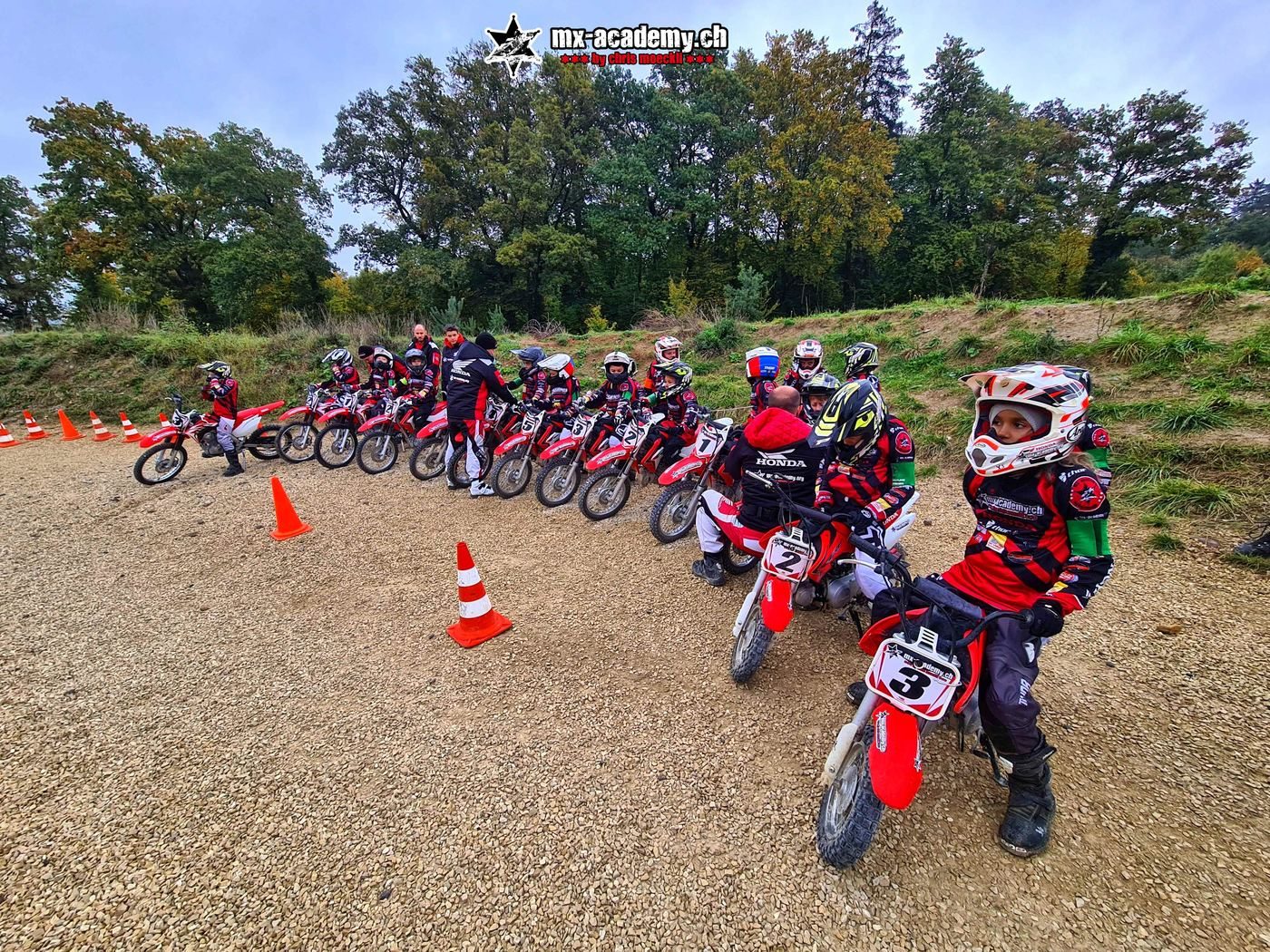 What to do in Switzerland with kids: children in helmets line up on small red Honda bikes beside traffic cones